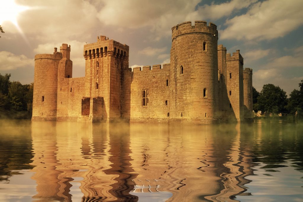 A castle surrounded by a body of water with Bodiam Castle in the background